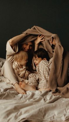 a woman and two children under a blanket