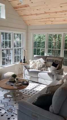 a living room filled with furniture and windows covered in wood planks on the ceiling