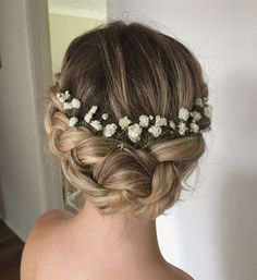 the back of a woman's head with flowers in her hair and braids