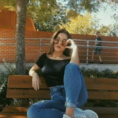 a woman sitting on top of a wooden bench