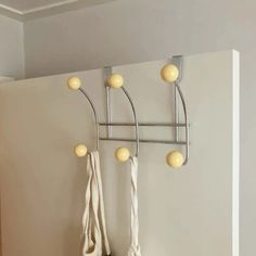 a wall mounted coat rack with three balls on it and two hooks hanging from the ceiling