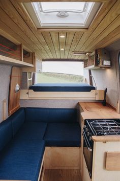 the interior of a small camper with blue couches and wood paneled walls