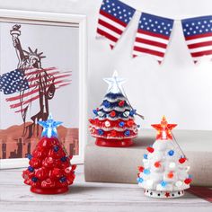 three patriotic christmas trees in front of an american flag bunting on a table with two framed photos