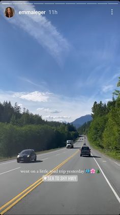 two cars are driving down the road with trees in the back ground and blue sky above