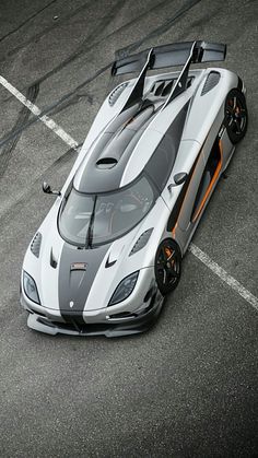 a white and orange sports car driving down a race track