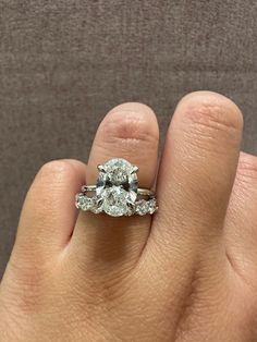 a woman's hand with a diamond ring on top of her left hand,