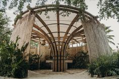 the inside of a wooden structure surrounded by greenery and palm trees in an outdoor setting