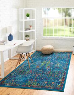 a room with a rug, chair and computer desk in front of a large window