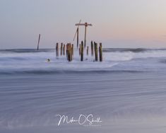 the water is choppy and foamy as it sits in front of some wooden posts