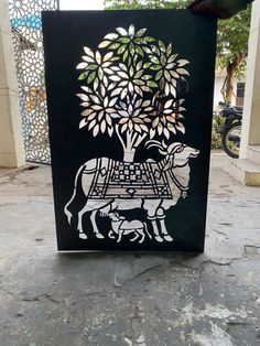 an art piece with a cow and tree in the center on a stone floor next to a building