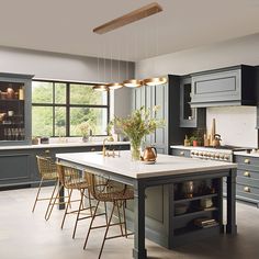 a large kitchen with gray cabinets and white counter tops, an island in the middle is surrounded by wicker chairs