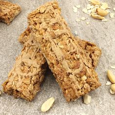 three granola bars sitting on top of a counter next to nuts and oats