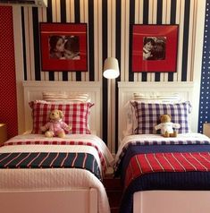 two twin beds in a room with striped walls and pictures on the wall behind them