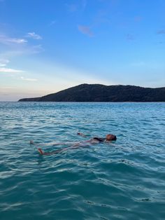 a person floating in the water with their head above the water's surface and an island in the distance