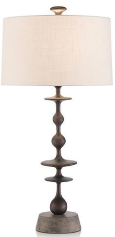 a table lamp with a white shade on it and a light in front of it