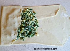 an uncooked pizza dough with spinach and cheese