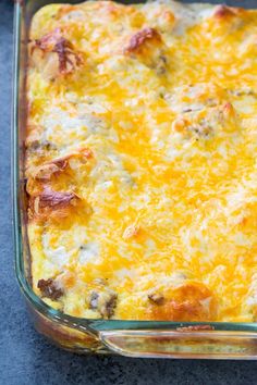 a casserole dish with meat and cheese in it sitting on a blue surface