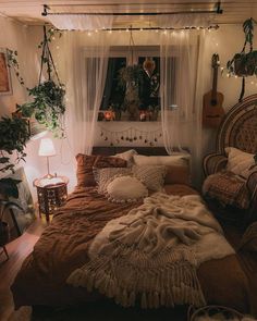 a bed sitting in a bedroom next to a window filled with plants and lights on the wall