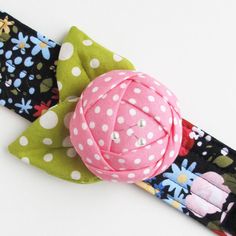 a close up of a flower and polka dot fabric headband on a white background