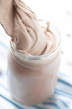 a jar filled with chocolate frosting on top of a blue and white table cloth