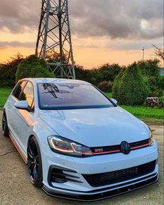 a white car parked in front of a tall tower with power lines on it's roof