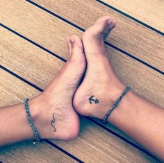 two people with tattoos on their feet sitting on a wooden floor next to each other