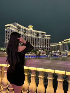 a woman is standing on a balcony looking at the hotel and casino buildings in the background