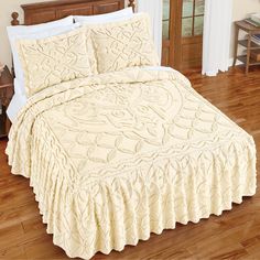 a bed with a white bedspread and matching comforter on top of it