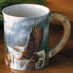 a coffee mug with an eagle painted on the front and sides, sitting on a wooden table