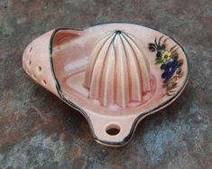 a pink ceramic dish with flowers on it sitting on a stone surface next to a wall