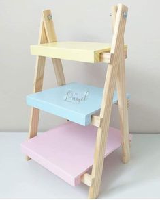 three tiered wooden shelf with personalized items on top and bottom shelves in pastel colors