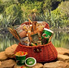 a picnic basket with snacks and drinks sitting on rocks