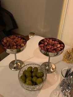 three bowls filled with nuts and olives on a table