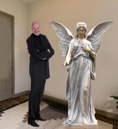 a man standing next to a statue of an angel with her hands on her hips