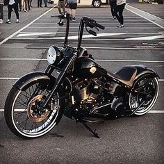 a black motorcycle parked in a parking lot with people walking around and onlookers