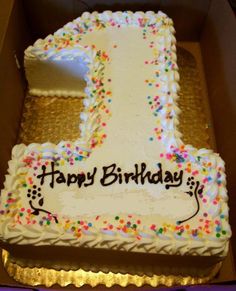 a birthday cake in a box with the number one on it and sprinkles