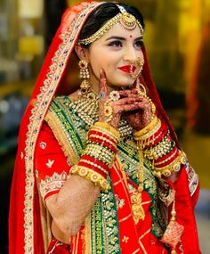 a woman dressed in red and green is holding her hands together while posing for the camera