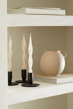 three white candles are sitting on a shelf