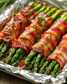 asparagus wrapped in bacon on top of tin foil with green onions and parsley