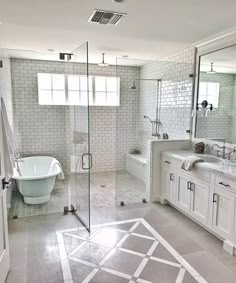 a white bathroom with glass shower doors and tub in the center, sink on both sides