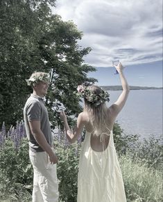 a man and woman standing next to each other in front of the water holding hands