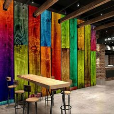 colorful wooden planks are painted on the wall in an industrial area with tables and stools