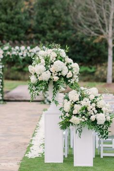 an outdoor ceremony with white flowers and greenery