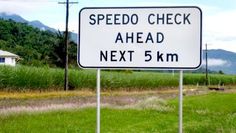 a speed limit sign on the side of a road in front of some grass and mountains