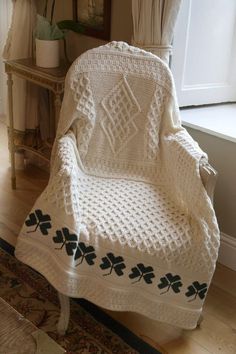 a crocheted irish blanket sitting on top of a chair in front of a window