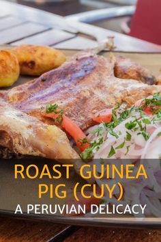 roast guinea pig cut on a plate with potatoes and carrots next to it, sitting on a wooden table