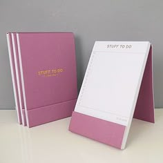 two pink notebooks sitting next to each other on a white counter top, with the words stuff to do written on them