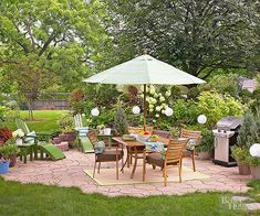 an outdoor dining area with patio furniture and umbrella in the middle, surrounded by greenery