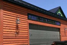 a car is parked in front of a wooden building with two garage doors on each side