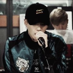 a boy in a baseball cap is singing into a microphone while another person looks on